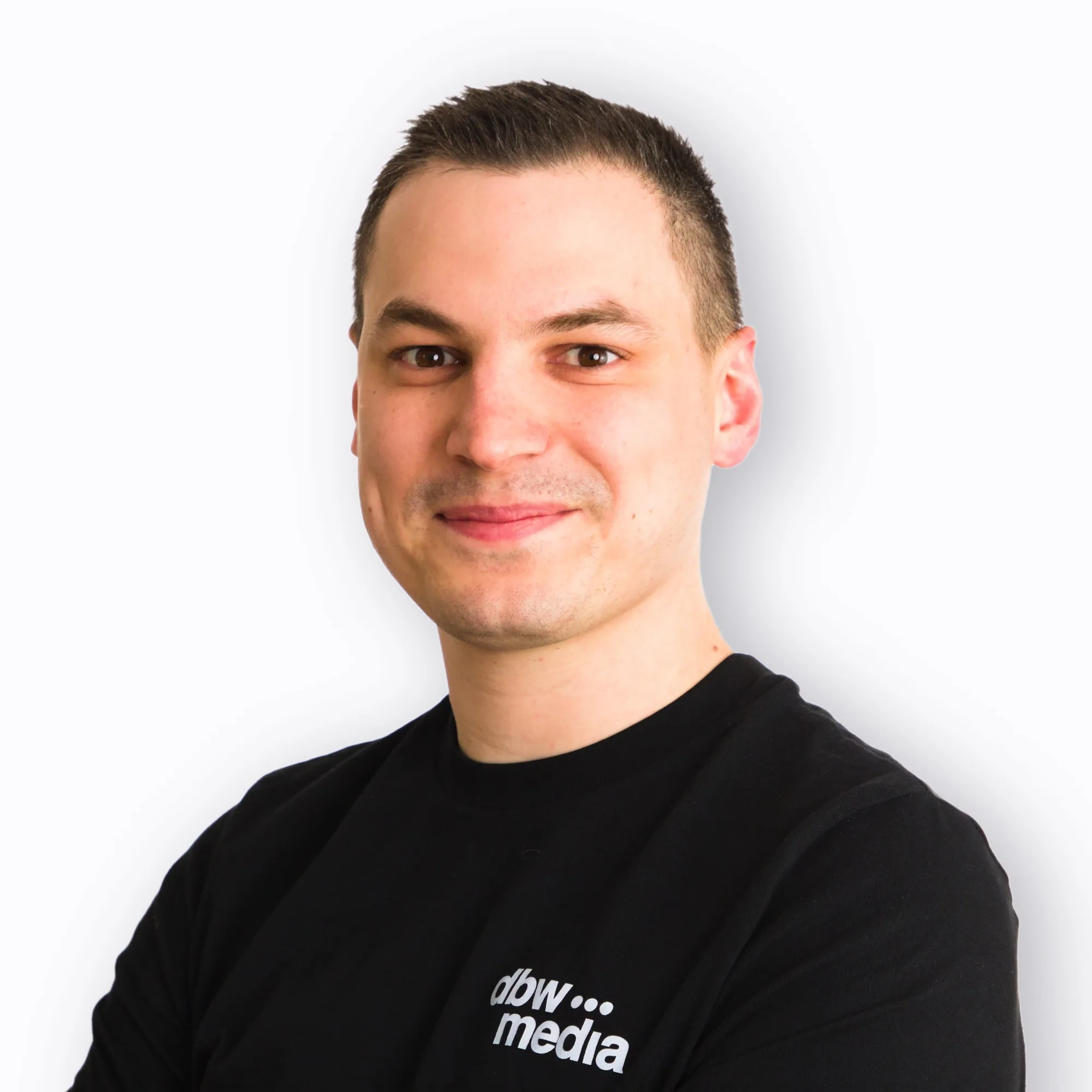 Dennis von dbw media, Portrait mit verschränkten Armen vor hellem Hintergrund